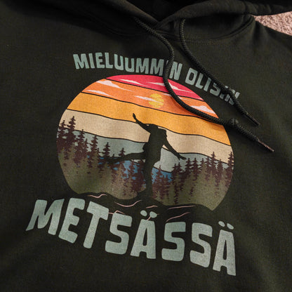 Tumma Mieluummin olisin metsässä -huppari retkeilijän siluetilla ja auringonlaskuprintillä, lähikuvassa.